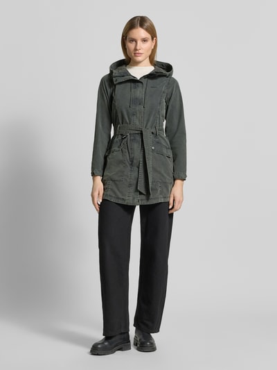Frauenmodel trägt Jacke mit Bindegürtel Modell 'PREA' von khujo aus Baumwoll-Mix, Regular-Fit, Kapuze, Label-Stitching, Ganzkörperansicht von vorne. Rückenlänge 37 cm, Schulterbreite 44 cm, Brustweite 45 cm, Ärmellänge 53 cm. Farbe dunkelgrün, glatte Textur.
