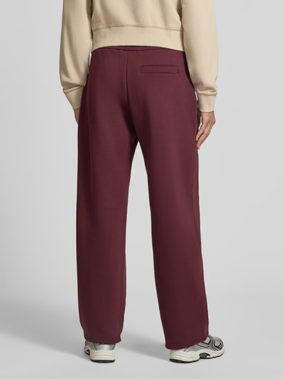Männermodel trägt Straight Fit Sweatpants aus Baumwoll-Mix mit Label-Detail von REVIEW in Dunkelrot, elastischer Bund, Ganzkörperansicht Rückansicht.