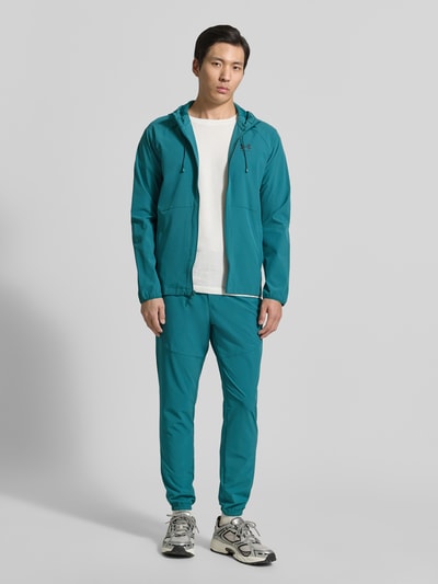 Männermodel trägt Regular Fit Jacke mit Logo-Print Modell 'Vibe' von Under Armour in Türkis, elastischer Material-Mix, Ganzkörperansicht von vorne.