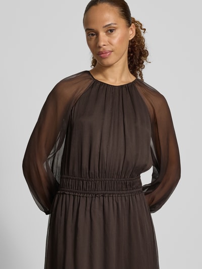 Vrouwenmodel draagt Maxikleid in semitransparentem Design van comma, donkerbruin met plooien, getailleerde pasvorm, ronde hals, met lange mouwen, ruglengte maat 36: 132 cm, borstwijdte 45 cm, mouwlengte 49 cm, Nahaufnahme Oberkörper