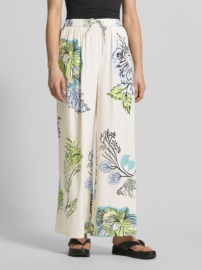 Frauenmodel trägt Stoffhose aus Seide-Mix von HERZENS, Loose-Fit, elastischer Bund mit Tunnelzug, florales Muster in Beige, Blau, Grün, Nahaufnahme Oberkörper. Bundweite bei Größe 36: 37 cm, Innenbeinlänge 76 cm.