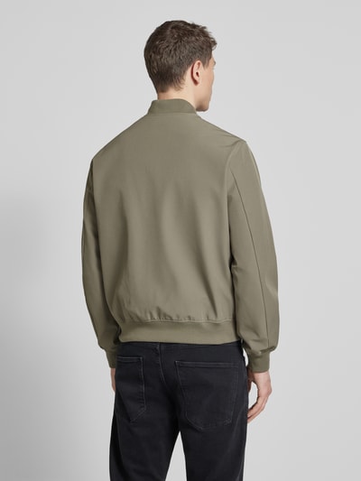 Männermodel trägt olivgrüne Bomberjacke mit Stehkragen Modell 'BLAASPEN' von Jack & Jones Premium, glatte Struktur, Ganzkörperansicht Rückansicht.