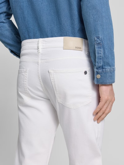 Männermodel trägt Regular Fit Jeans aus Baumwoll-Mix Modell 'MAINE' von BOSS Orange in Unifarbe Weiß, Logo-Applikation, Ganzkörperansicht Rückansicht.