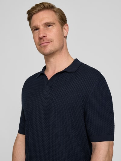 Mężczyzna nosi Regular Fit Poloshirt aus reiner Baumwolle Modell 'NATALO' od BOSS, granatowy, pikowana faktura, krój regular fit, krótki rękaw, widok z przodu zbliżenie na górną część ciała.