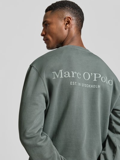 Männermodel trägt Regular Fit Sweatjacke aus reiner Baumwolle von Marc O'Polo in Uni-Optik mit Label Print und gerippten Abschlüssen, Ganzkörperansicht Rückansicht.