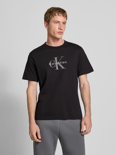 Männermodel trägt T-Shirt mit Label-Print und Rundhalsausschnitt von Calvin Klein Jeans, Regular-Fit, reine Baumwolle, Vorderansicht Ganzkörperansicht.