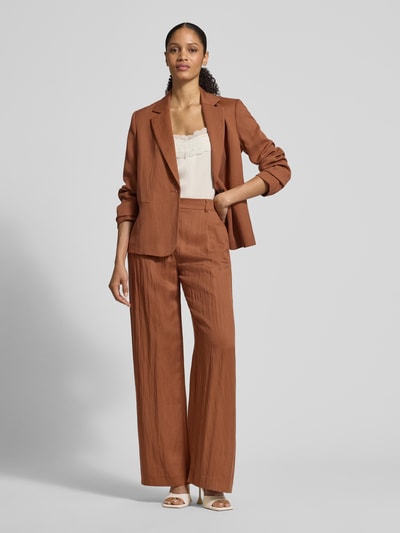 Frauenmodel trägt Stoffhose mit Eingrifftaschen und Gesäßleistentaschen von Jake*s Collection in Braun, Loose Fit, Lyocell-Mix, Ganzkörperansicht von vorne.