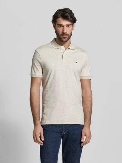 Männermodel trägt Regular Fit Poloshirt aus reiner Baumwolle Modell 'LIQUID COTTON' von Tommy Hilfiger in Melange-Optik, Logo-Stitching, Polokragen, Kurzarm, gerippte Abschlüsse, Seitenschlitze, natürliche Farbtonstruktur, Ganzkörperansicht von vorne.
