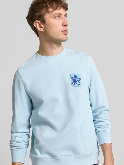 Mannelijk model draagt lichtblauw Regular Fit Sweatshirt met florale applicatie model 'Felica' van Blend, katoen, ronde hals, detailopname bovenlichaam.