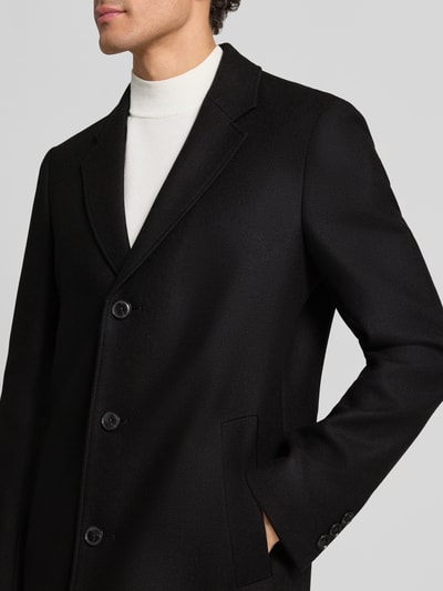 Männermodel trägt Mantel mit einreihiger Knopfleiste von BOSS aus schwarzem Wollmix, unifarben, Nahaufnahme Oberkörper.