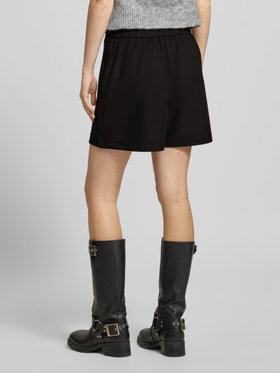 Mädchen trägt Regular Fit Shorts mit Viskose-Anteil Modell 'BOSELLA' von Pieces, czarny, gładki, elastyczny pas, rozcięcia po bokach, label stitching, ganzkörperansicht rückansicht.