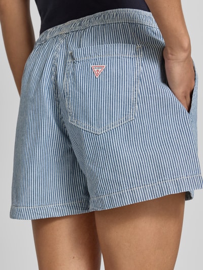 Frauenmodel trägt Shorts mit elastischem Bund und Kordelzug von Guess Jeans aus Reine Baumwolle, Loose-Fit, mit Seitliche Eingrifftaschen, Ganzkörperansicht Rückansicht.