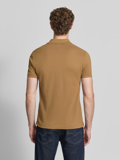 Männermodel trägt Slim Fit Poloshirt aus reiner Baumwolle von Lacoste in Braunton, klare Linien, glatte Textur, Ganzkörperansicht Rückansicht.