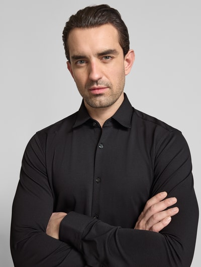 Männermodel trägt Slim Fit Businesshemd in Struktur-Optik Modell 'ERMO' von HUGO in Schwarz, Piqué, Nahaufnahme Oberkörper.