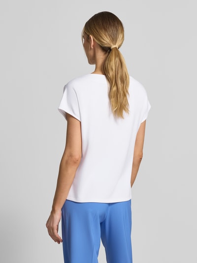 Frauenmodel trägt T-Shirt mit Zierknöpfen und Rundhalsausschnitt von Comma, Viskose-Mix mit Stretch-Anteil, Relaxed-Fit, Rückenlänge 58 cm, Ärmellänge 13 cm, Unifarbe Weiß, glatte Textur, Ganzkörperansicht Rückansicht.