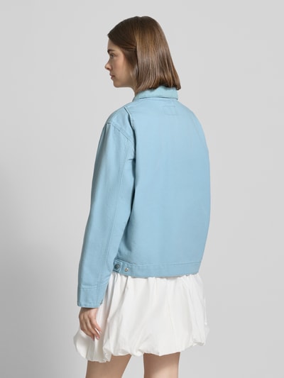 Frauenmodel trägt Jacke mit Label-Detail von Carhartt Work In Progress in Hellblau, Reine Baumwolle, Relaxed-Fit, Rückenansicht Ganzkörperansicht.