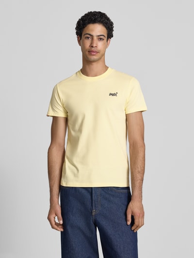 Männermodel trägt Regular Fit T-Shirt mit Logo-Stitching von Superdry in Gelb, reine Baumwolle, Rundhalsausschnitt, Ganzkörperansicht von vorne.