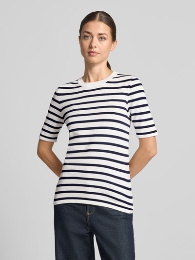 Frauenmodel trägt Regular Fit Pullover in Strick-Optik Modell "LULS" von ICHI, weiß mit dunkelblauen Streifen, Viskose-Mix, Kurzarm, Rundhalsausschnitt, Ganzkörperansicht von vorne.