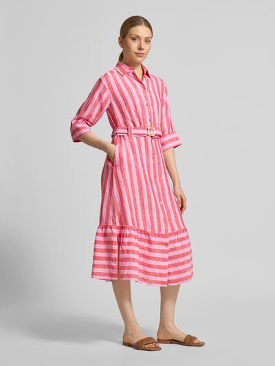 Modelka kobieca ma na sobie Hemdblusenkleid aus Leinen mit Gürtel und Eingrifftaschen von Christian Berg Woman, różowo-białe pionowe pasy, długość midi, lniany materiał, pasek, kieszenie boczne, krój A-linia, długość tyłu 115 cm, szerokość w rozmiarze 36: 45 cm, rękaw 3/4, długość rękawa 37 cm, widok całej sylwetki z przodu.
