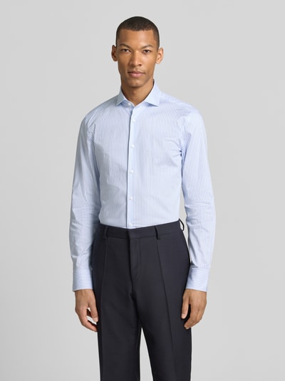 Männermodel trägt Slim Fit Businesshemd mit extra langem Arm Modell 'H-HANK-SP-C1' von Seidensticker, Optik: Allover-Muster, hellblau-weiß gestreift, durchgehende Knopfleiste, Haifischkragen, Baumwoll-Mix, bügelleicht, Ganzkörperansicht von vorne.