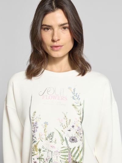 Frauenmodel trägt Boxy Fit Sweatshirt mit O-Neck und Blumen-Print im 2er-Pack von Christian Berg Woman aus elastischem Material-Mix mit Modal-Anteil, Oversized-Look, zartes Weiß mit farbigem Blumen-Print, Nahaufnahme Oberkörper.
