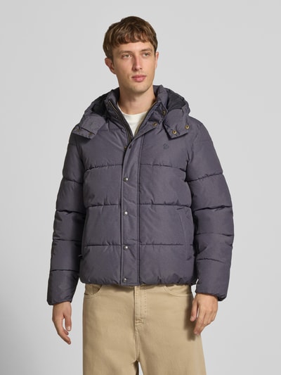 Männermodel trägt Steppjacke mit Kapuze und Reißverschluss von Superdry in Grau, sichtbare Knopfleiste, Ganzkörperansicht von vorne. Regular Fit, Stehkragen, verdeckter Reißverschluss, Rückenlänge 71 cm, Schulterbreite 50 cm, Brustweite 56 cm, Ärmellänge 83 cm.