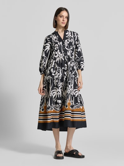 Frauenmodel trägt Midikleid mit Eingrifftaschen und 3/4-Arm von Emily Van den Bergh in Allover-Look, Schwarz-Weiß mit Braun, Reine Baumwolle, A-Linie, Knopfleiste, V-Ausschnitt, Ganzkörperansicht von vorne. Rückenlänge bei Größe 36: 126 cm, Brustweite 43 cm, Ärmellänge 46 cm.