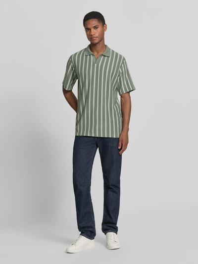 Männermodel trägt Regular Fit Poloshirt mit V-Ausschnitt Modell 'HARRY' von Jack & Jones Premium, grün-weiß gestreift, Baumwoll-Mix, Ganzkörperansicht von vorne.