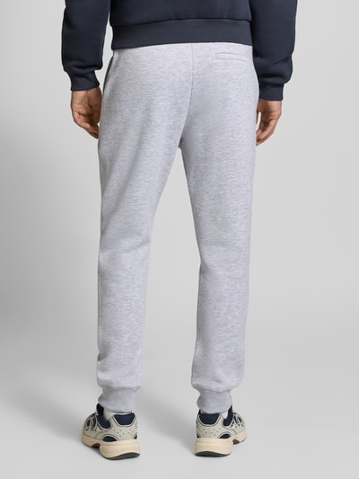 Männermodel trägt Slim Fit Sweatpants mit Logo-Stitching von REVIEW in Hellgrau, Baumwoll-Mix, Gesäßtasche, elastischer Bund, Ganzkörperansicht Rückansicht.