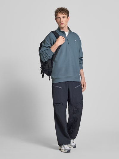 Männermodel trägt Relaxed Fit Sweatshirt mit Stehkragen und Reißverschluss von The North Face in Blau, reine Baumwolle, Label-Stitching; Ganzkörperansicht von vorne.