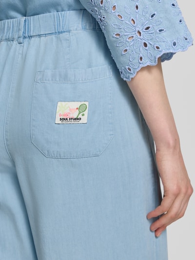 Frauenmodel trägt Hose mit Lochstickerei und französischen Eingrifftaschen von Smith and Soul aus Lyocell in Hellblau, Detailaufnahme Rückansicht.