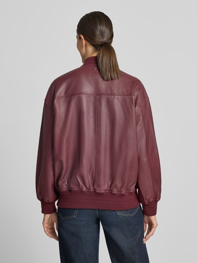 Frauenmodel trägt Regular Fit Bomberjacke aus reinem Schafsleder Modell 'Ruby' von MOS MOSH in Bordeaux mit Stehkragen, Rückansicht, Ganzkörperansicht. Rückenlänge 65 cm, Schulterbreite 55 cm, Brustweite 67 cm, Ärmellänge 53 cm, Kontext: Damen Bomberjacke, elastische Abschlüsse, Eingrifftaschen, Reißverschluss.