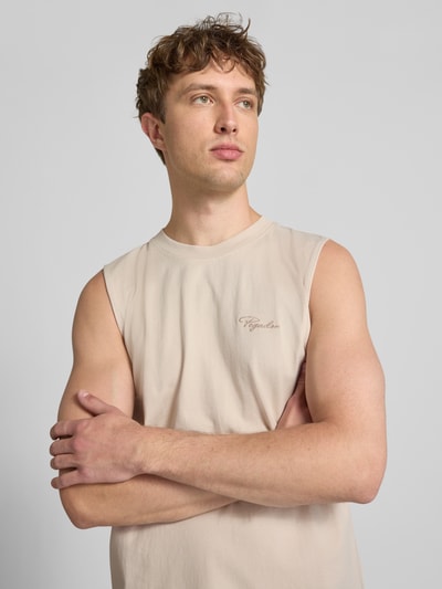 Männermodel trägt Tanktop mit Label-Stitching und Rundhalsausschnitt von Pegador in Beige, reine Baumwolle, Relaxed Fit, Nahaufnahme Oberkörper.