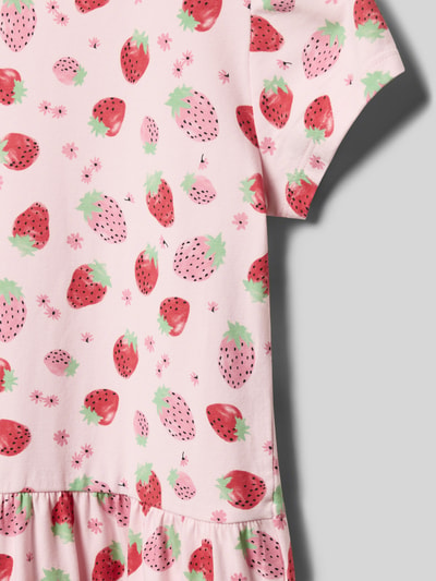 Mädchen trägt Leicht ausgestelltes Freizeitkleid aus Baumwoll-Mix von s.Oliver RED LABEL mit Erdbeermotiv auf rosa Grund, Nahaufnahme Oberkörper.