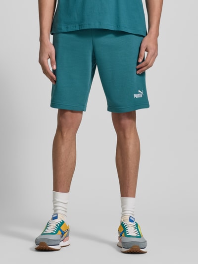 Männermodel trägt Shorts mit Label-Stitching von PUMA PERFORMANCE in Türkis, Baumwoll-Mix, Regular Fit, Ganzkörperansicht von vorne.