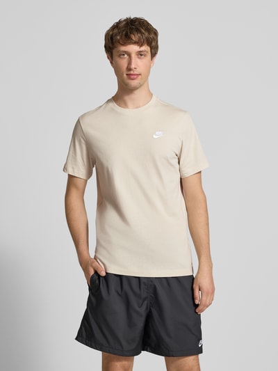 Männermodel trägt T-Shirt mit Label-Stitching von Nike in Beige, Reine Baumwolle, Regular-Fit, Rundhalsausschnitt, Ganzkörperansicht von vorne. Rückenlänge bei Größe M: 73 cm.