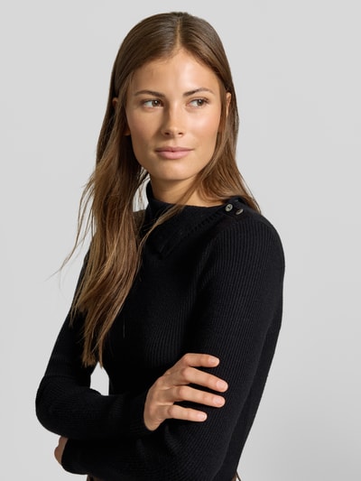 Frauenmodel trägt Slim Fit Pullover aus Viskose-Mix in Strick-Optik von MYON, schwarze Farbe, Knopfleiste, Nahaufnahme Oberkörper.