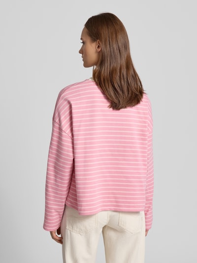 Vrouwenmodel draagt Regular Fit Longsleeve uit puur katoen van OH APRIL in lichtroze met witte strepen, ruglengte bij maat S 53 cm, geheel achteraanzicht.