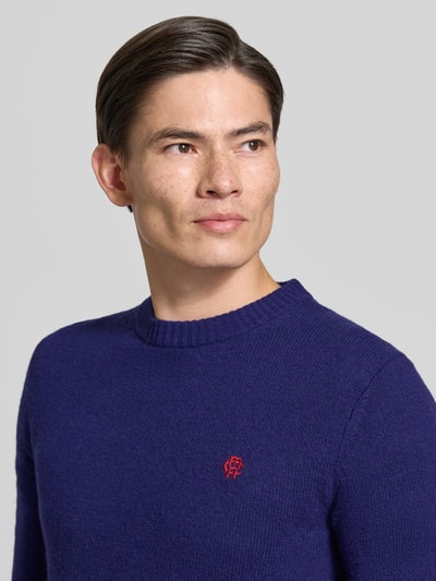 Männermodel trägt Slim Fit Strickpullover aus reiner Wolle mit Label-Stitching von MCNEAL in Dunkelblau, Nahaufnahme Oberkörper. Gerippte Abschlüsse, Rückenlänge 66 cm, Ärmellänge 69 cm.
