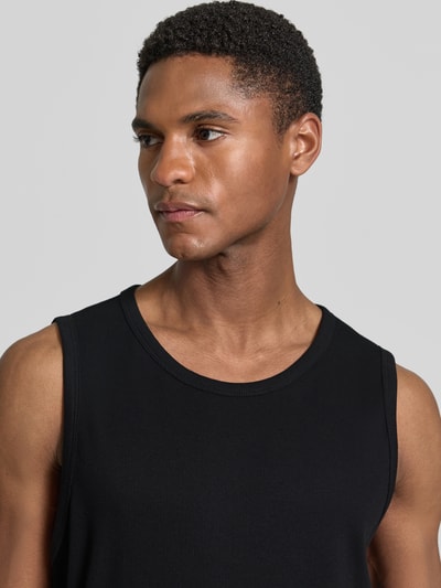 Mężczyzna nosi Slim Fit Tank Top aus Baumwoll-Mix von s.Oliver RED LABEL, czarny, krój slim fit, szerokie ramiączka, okrągły dekolt, bawełna, faktura drobnego ściągacza, widok na górną część ciała z przodu