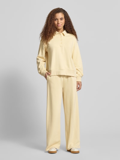 Modelka nosi Wide Fit Sweatpants mit elastische Bund od Gina Tricot w kolorze jasnokremowym, mieszanka bawełny, krój wide fit i relaxed fit, długość wewnętrzna nogawki w rozmiarze S: 76 cm, widok całej sylwetki z przodu.