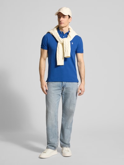 Männermodel trägt Regular Fit Poloshirt aus reiner Baumwolle von Polo Ralph Lauren in Uniblau mit Polokragen und Logo-Detail, Ganzkörperansicht von vorne.