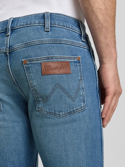 Männermodel trägt jeans in lichtblauw met steekzakken, label Wrangler, slim fit, model 'Greensboro', used-look, mix van katoen en elastaan, context: heren jeans van Wrangler, bandwijdte bij maat 32/32: 42 cm, binnenbeenlengte bij maat 32/32: 77 cm, detailopname rug.