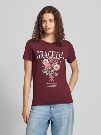 Frauenmodel trägt Regular Fit T-Shirt aus reiner Baumwolle 'ONLLUCY' von ONLY in Dunkelrot mit Blumenprint, Damen T-Shirt von ONLY, Nahaufnahme Oberkörper.