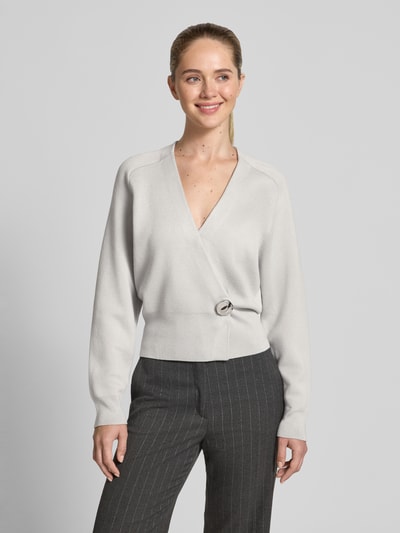 Frauenmodel trägt Cardigan im Wickel-Look - curated by Isabelle Hartmann von Style Icon Collection in Hellgrau mit V-Ausschnitt, Lockerer-Schnitt, Knopfverschluss und gerippten Ärmelabschlüssen, Ganzkörperansicht von vorne.
