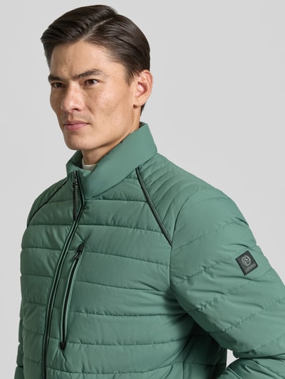Männermodel trägt Steppjacke mit Stehkragen und Reißverschlusstaschen von LERROS in grün, Regular Fit, Nahaufnahme Oberkörper.