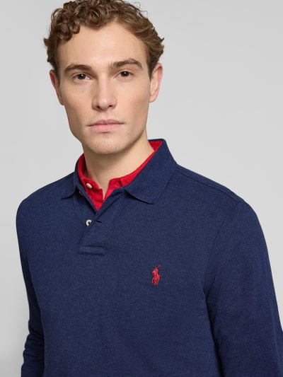 Männermodel trägt Slim Fit Poloshirt aus reiner Baumwolle von Polo Ralph Lauren in Unifarbe Blau mit Logo-Detail, Nahaufnahme Oberkörper.