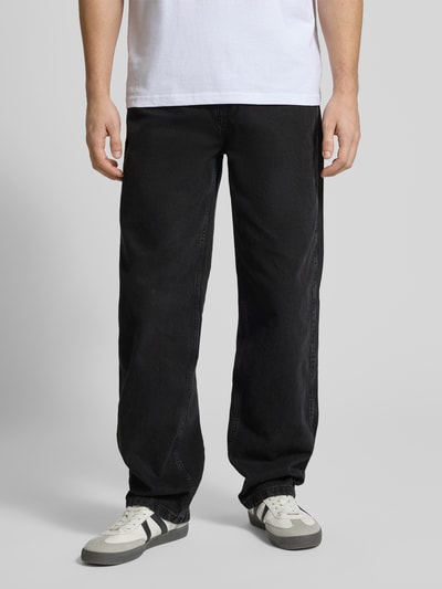 Männermodel trägt Baggy Jeans im 5-Pocket-Design mit Logo-Stitching von KARL KANI, schwarze Baumwolle, Baggy Fit, Ganzkörperansicht von vorne.
