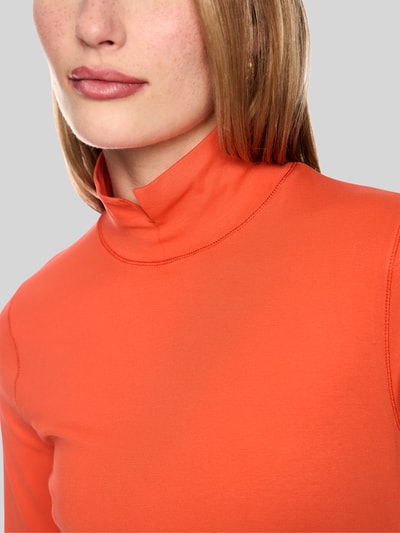 Frauenmodel trägt Longsleeve mit Stehkragen und Zierknöpfen von Marc Cain in Orange, Baumwoll-Elasthan-Mix, Nahaufnahme Oberkörper.