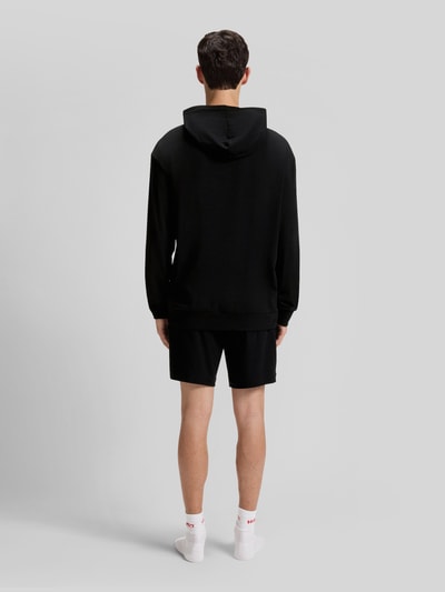 Männermodel trägt Regular Fit Hoodie aus Baumwoll-Mix Modell 'LAZE' von HUGO in Schwarz, Sweat-Optik, Ganzkörperansicht Rückansicht